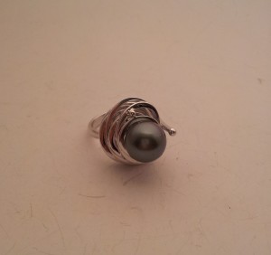 Anello artigianale in oro bianco con montatura particolare composta da cerchi irregolari e concentrici e, incastonata al centro, una perla Thaiti