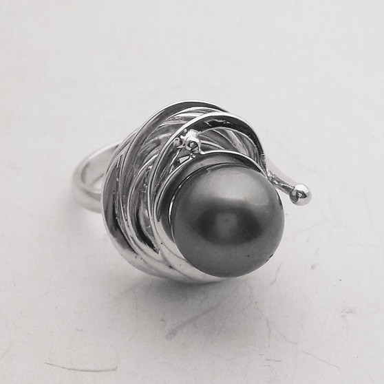 Anello artigianale in oro bianco con perla Tahiti incastonata al centro su una montatura particolare composta da cerchi irregolari e concentrici