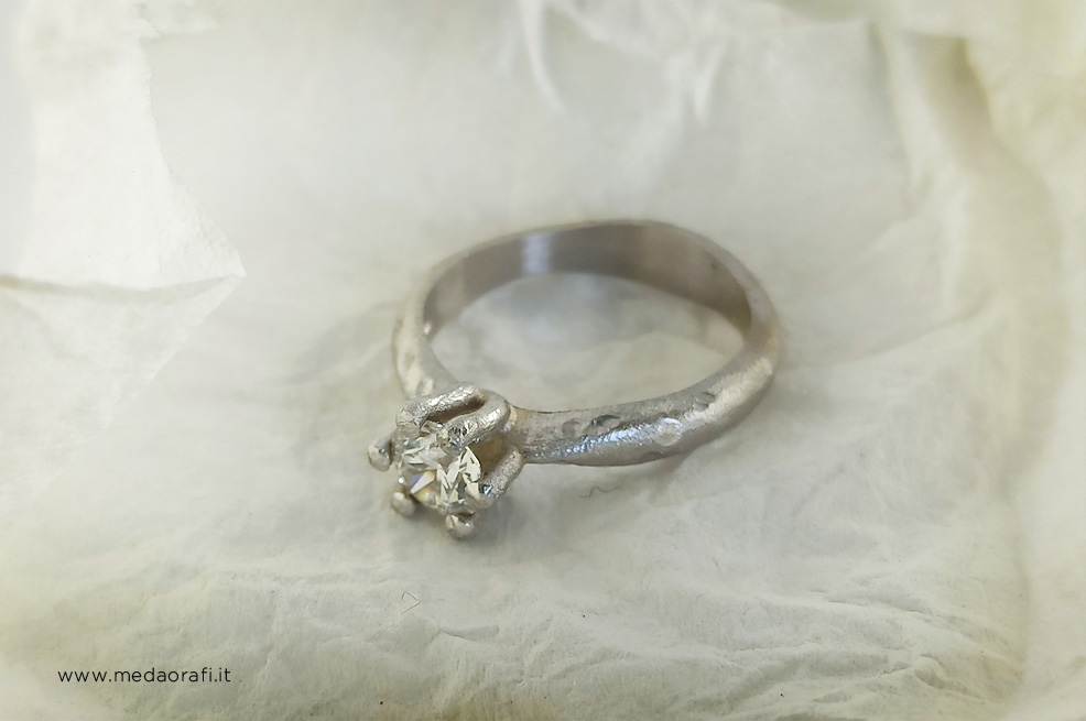 Anello di fidanzamento in oro bianco 18 kt e diamante in un cartina spiegazzata
