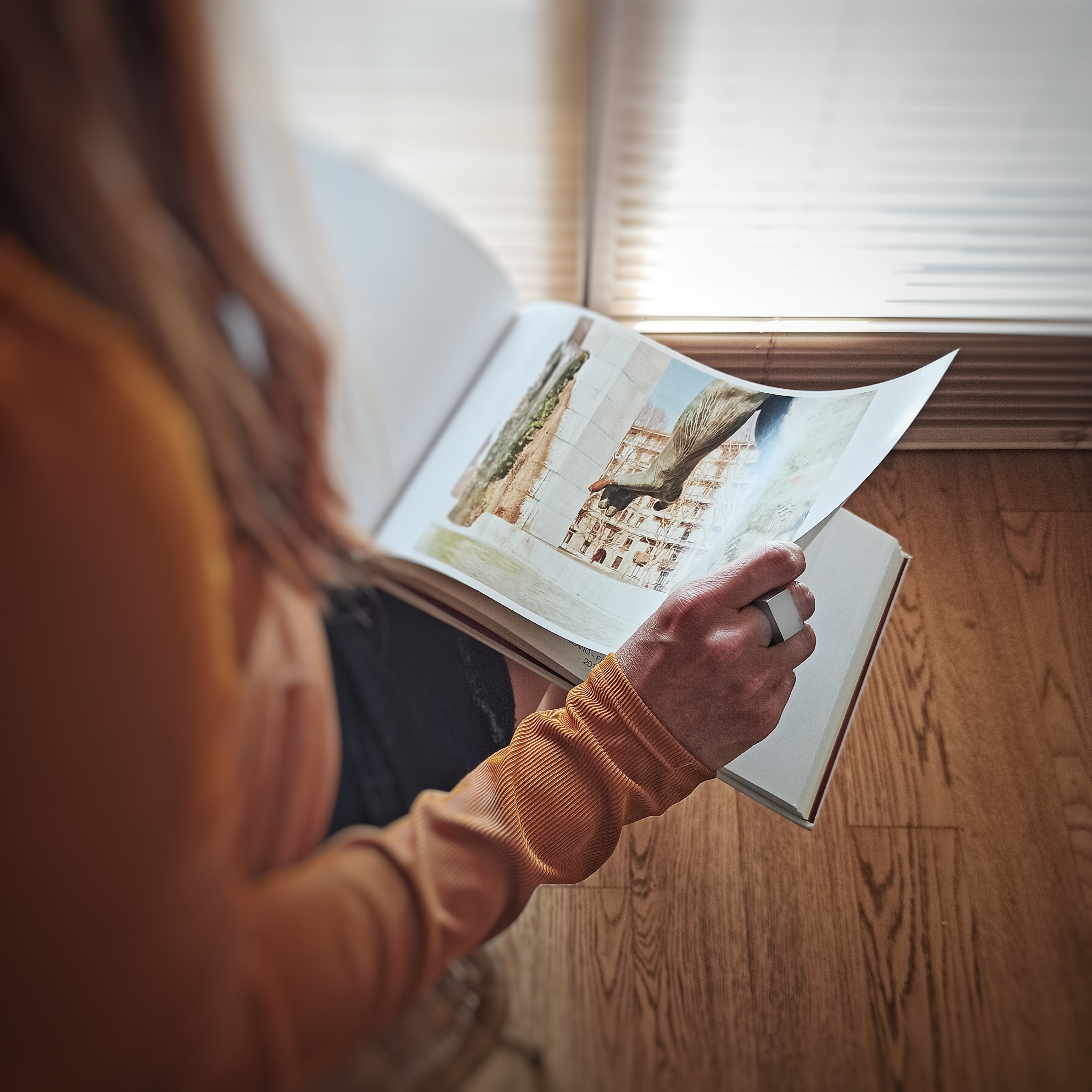 Una donna sfolia un libro di fotografia con un anello Bullone in acciaio