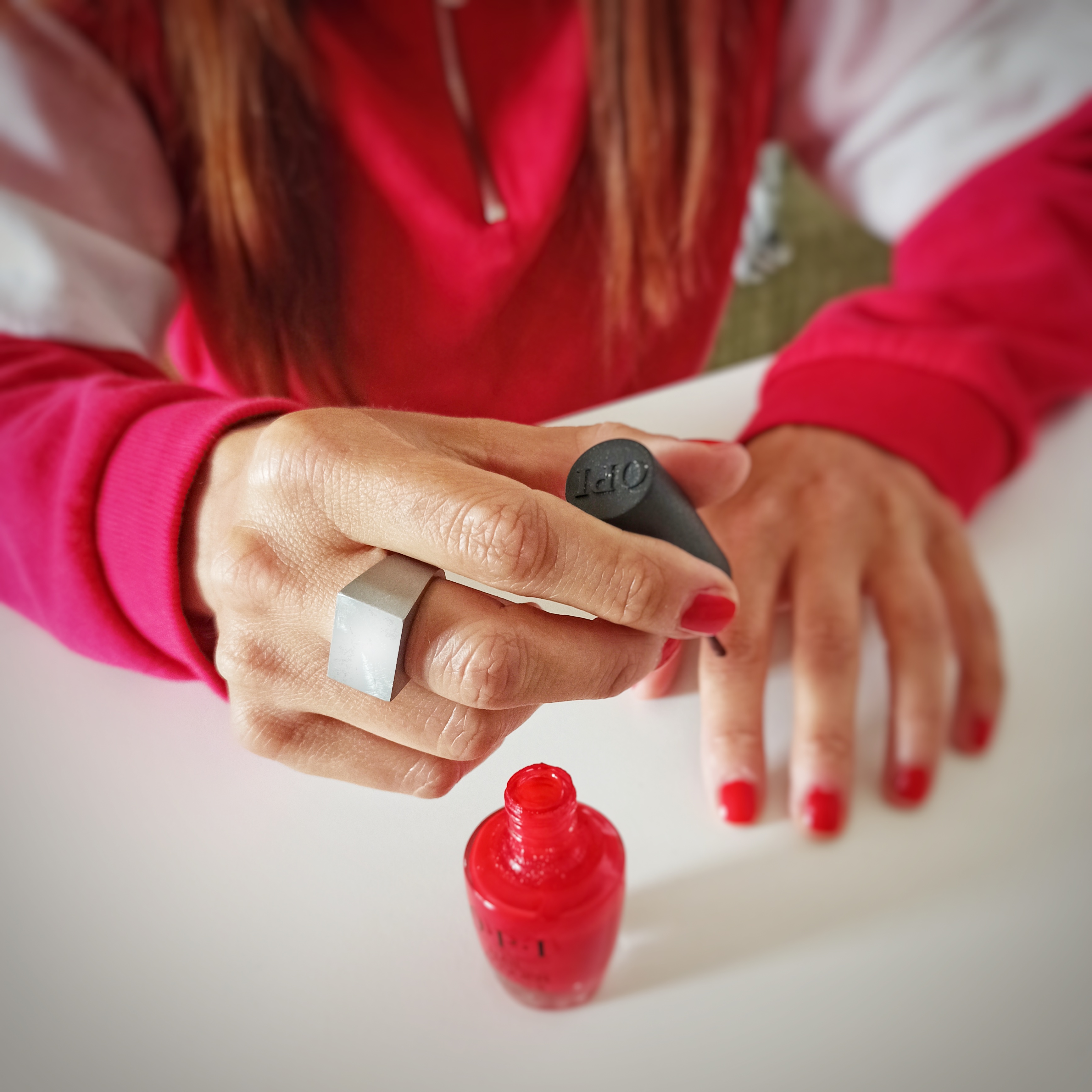 Mani di donna con anello in aciaio mentre applicano lo smalto per unghie