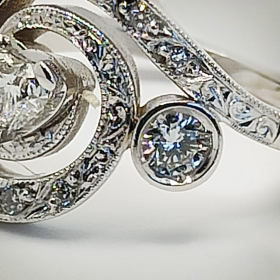 Particolare dei vari diamanti di un anello in oro bianco con diamante centrale a cuore, vista superiore con il dettaglio degli spessor