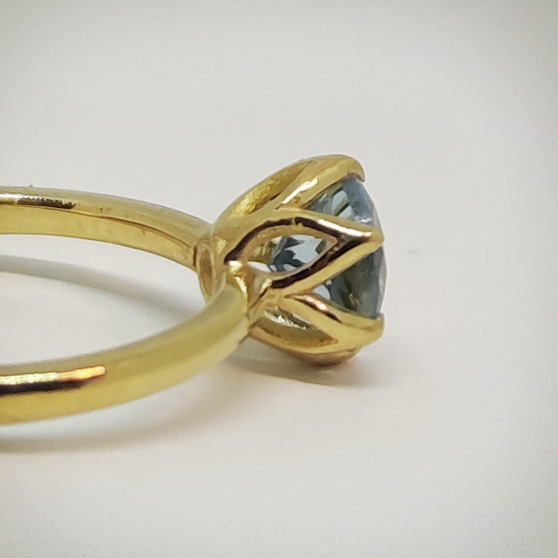 Anello in oro con acquamarina, dettaglio delle griffes a fiore