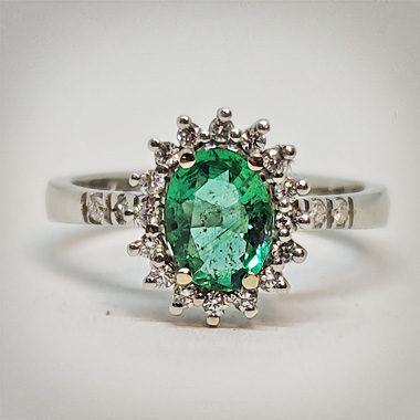 Vista frontale di anello in oro bianco con smeraldo taglio ovale e diamanti con griffes a triangolo