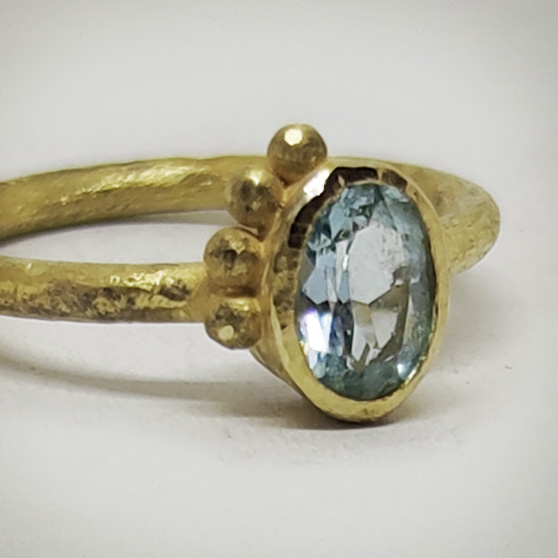 La lucentezza dell'acquamarina incassata in un anello in oro grezzo