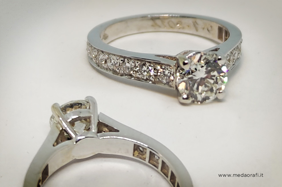 Anello di fidanzamento con diamante centrale e brillanti sul gambo, vista di 3/4 e il retro del castone 